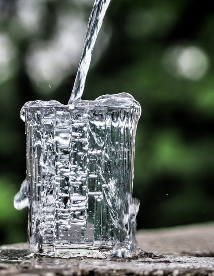 Close-up of water being poured into a glass, creating a dynamic splashing effect.